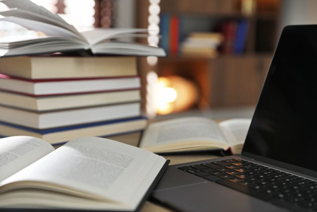 muchos libros y portatil sobre mesa en interior primer plano